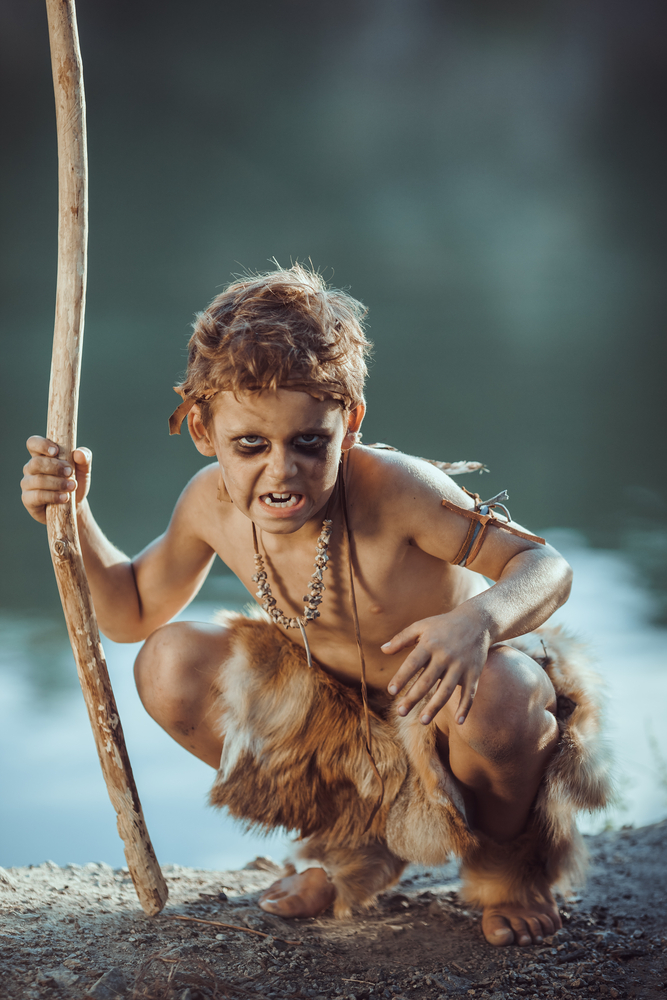 An angry boy dressed as a caveman, showing our connection to the reptilian brain and our primitive history.