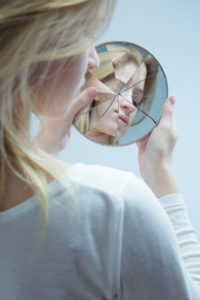 We feel pressured and controlled when measured against a version of us that doesn't exist, like this woman's fragmented vision as she looks in the mirror.